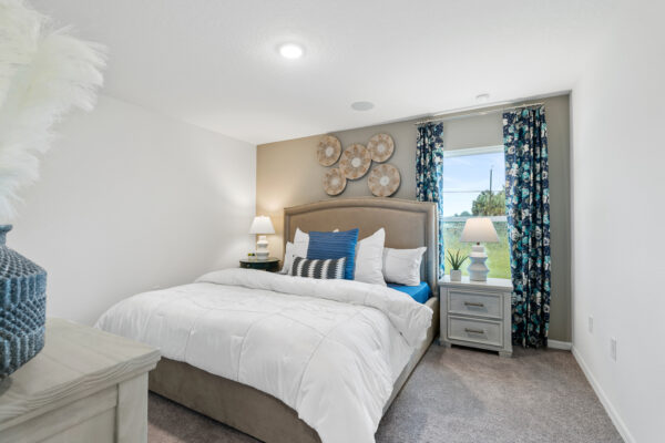 The blue and white decorated master bedroom in the Sylvester floorplan in the Value collection by Holiday Builders.