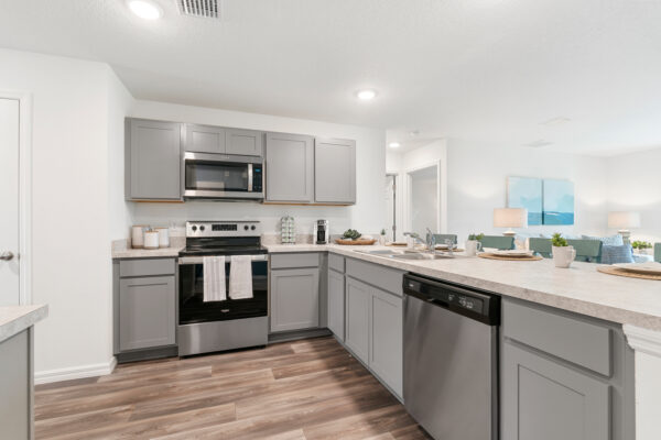 The kitchen featuring stainless steel appliances and gray cabinets in the Sylvester floorplan from the Value collection by Holiday Builders.