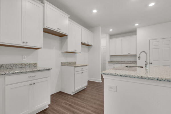 An all-white kitchen with quartz countertops in the Ariana floorplan from the Cornerstone collection by Holiday Builders.