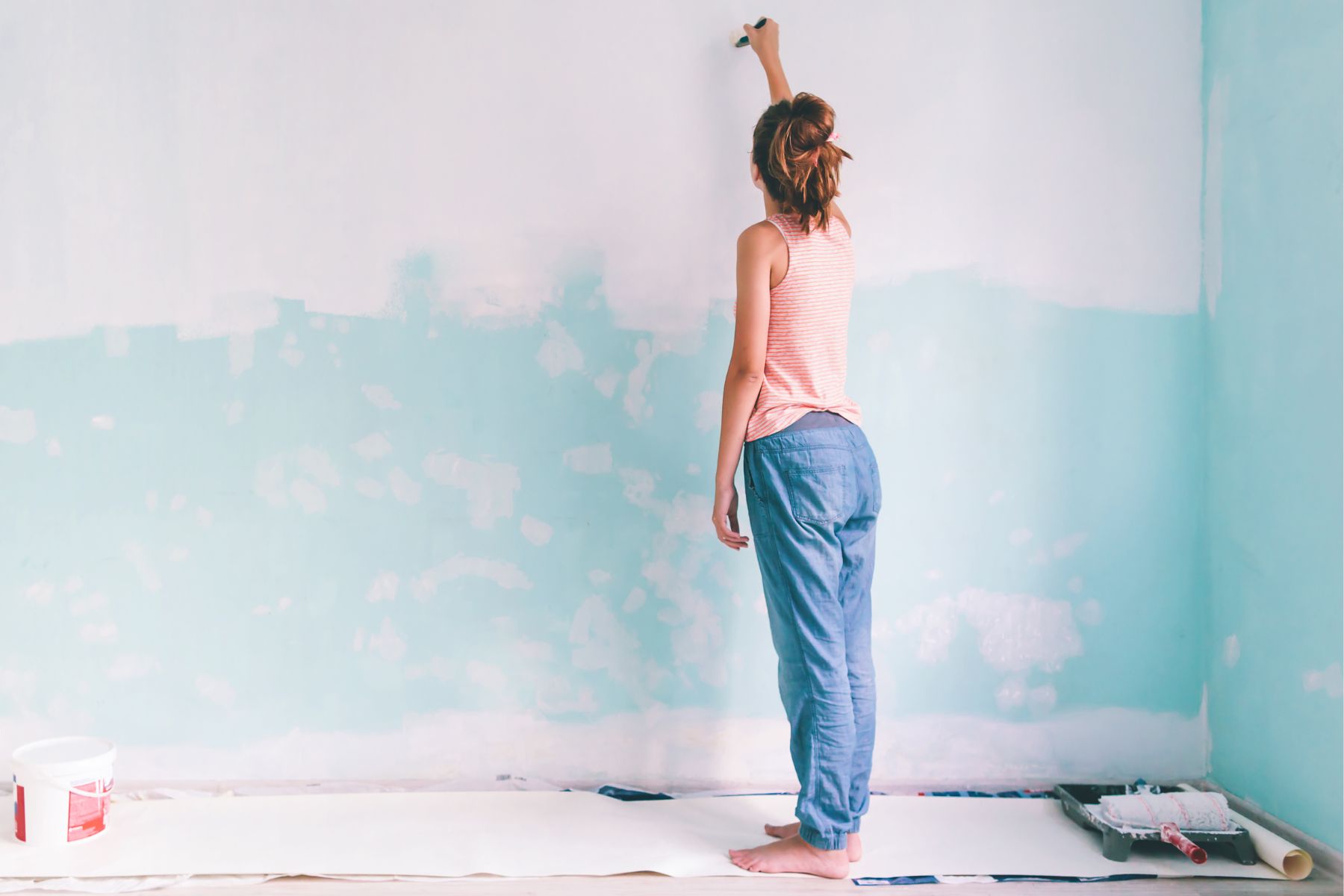 A photo of a woman painting a wall.